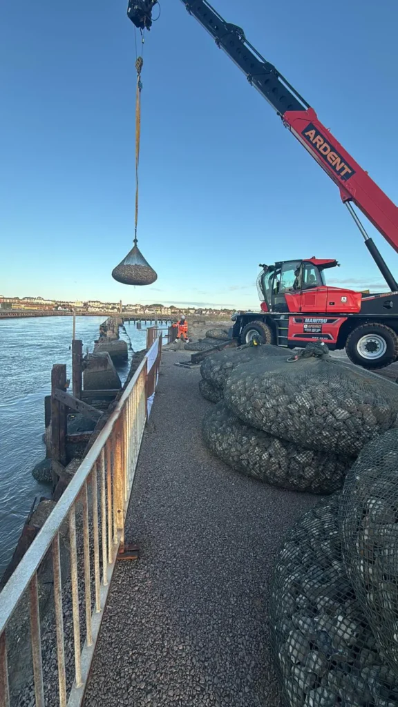 Crane lifting a rock bag into place for coastal defence reinforcement in Great Yarmouth