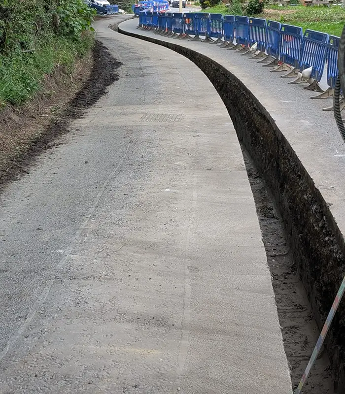 Concrete-lined utility trench running alongside a hedge