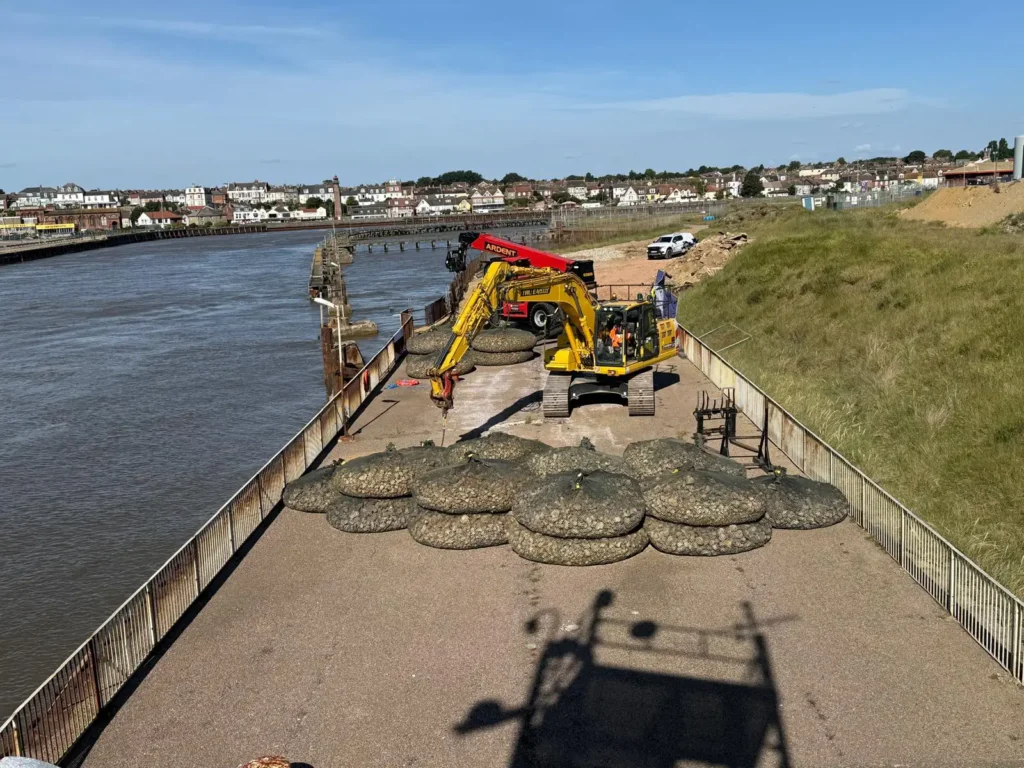 Excavator placing rock bags along the riverbank in Great Yarmouth