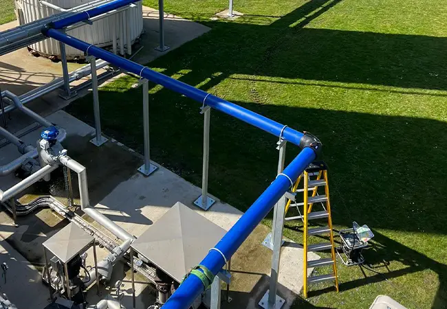 Blue overground water main on brackets crossing a factory site