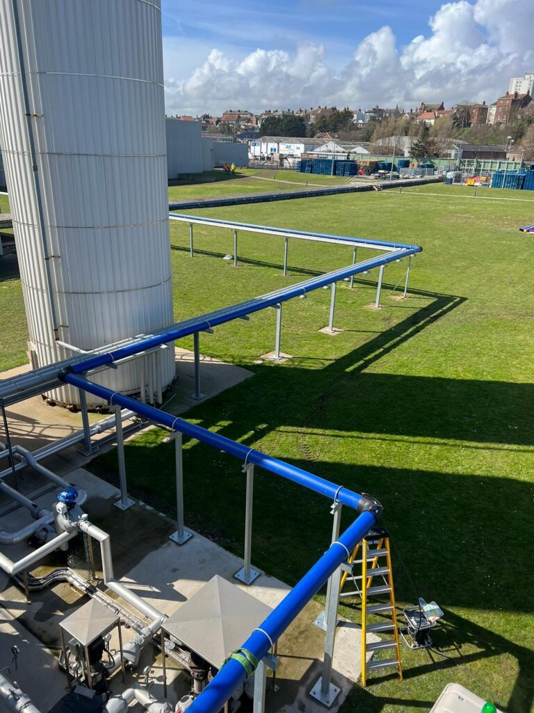 Blue overground water main rising beside a building at the Birds Eye factory, Lowestoft